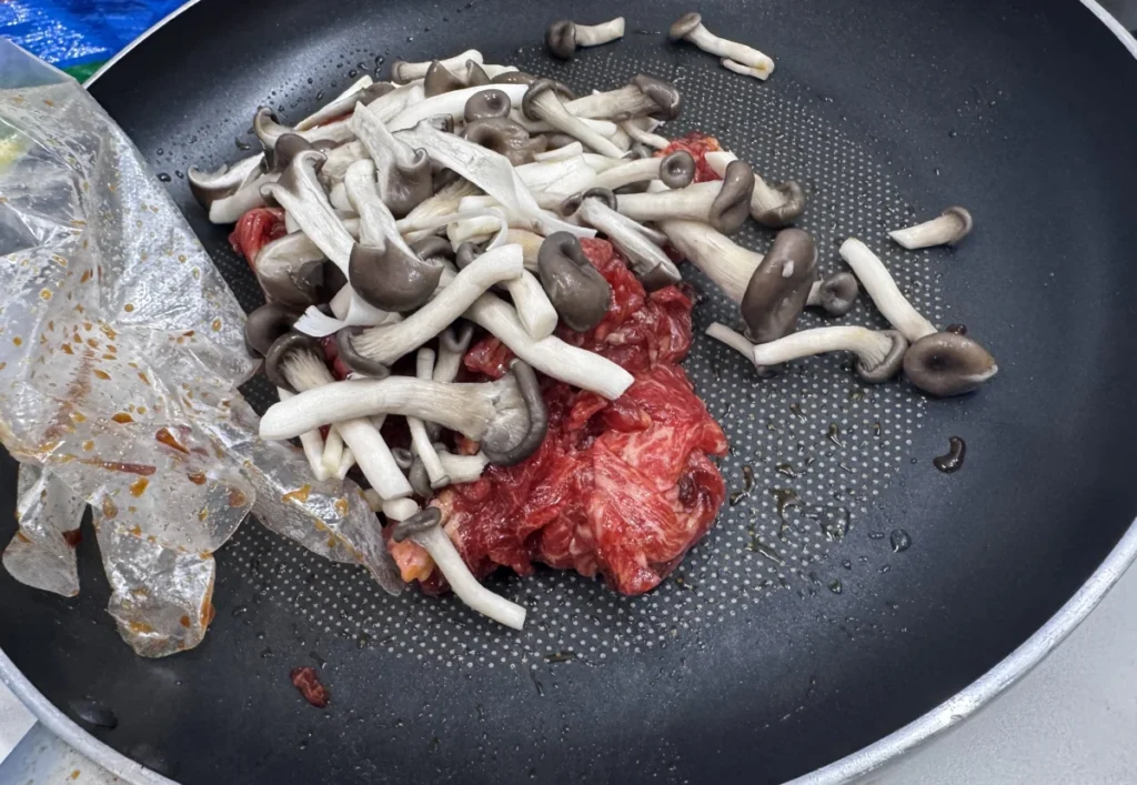 양념한 소불고기에 느타리버섯을 넣고 팬에 조리 시작하는 장면