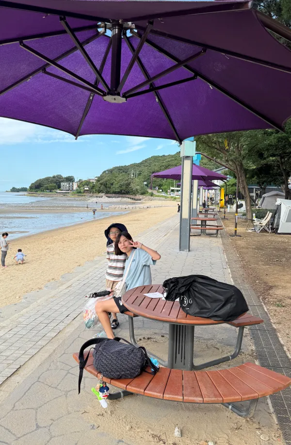 동막해수욕장 보라색 파라솔 아래에서 가족이 쉬는 모습